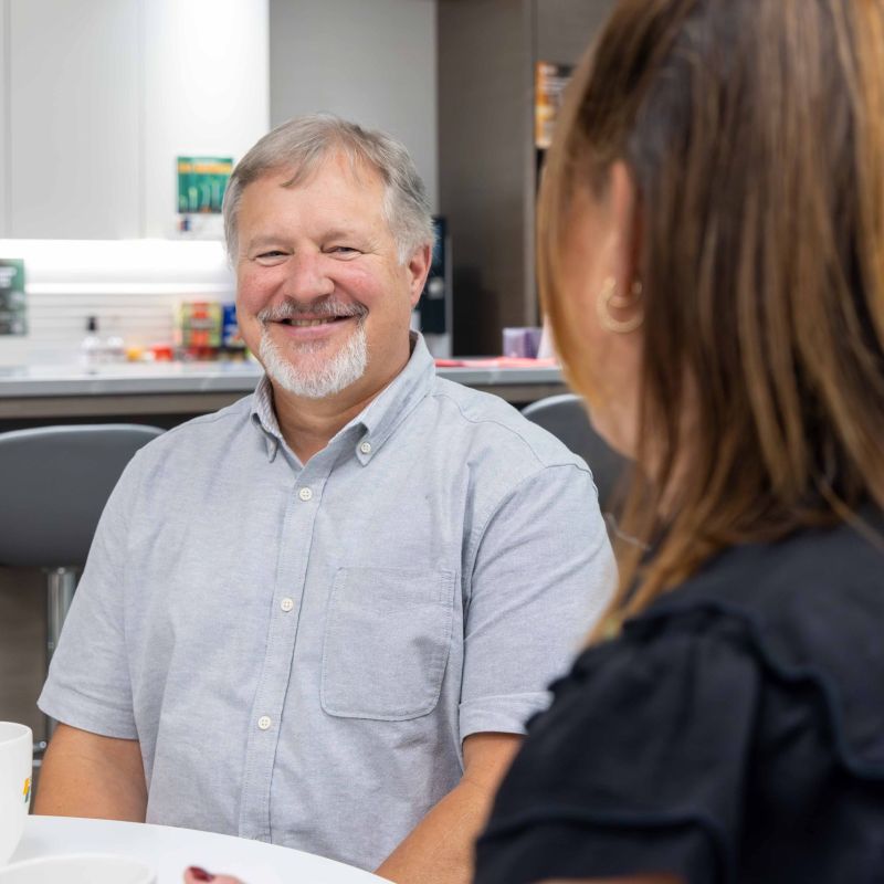 Smiling man at Surerus Murphy Joint Venture team's office kitchen, capturing teamwork and collaboration, emphasizing corporate photography services.
