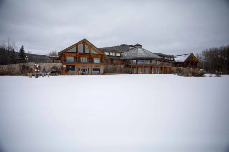 Gallery of the world's largest log home at Moberly Lake, featuring exterior views, the great room's 52ft ceiling, aerial shots, dining area, home theater, wine cellar, kitchen, and workout room with a pool and hot tub.