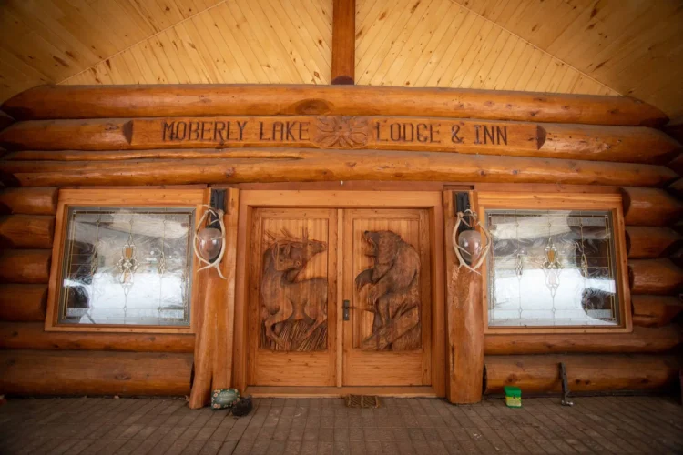 Gallery of the world's largest log home at Moberly Lake, featuring exterior views, the great room's 52ft ceiling, aerial shots, dining area, home theater, wine cellar, kitchen, and workout room with a pool and hot tub.