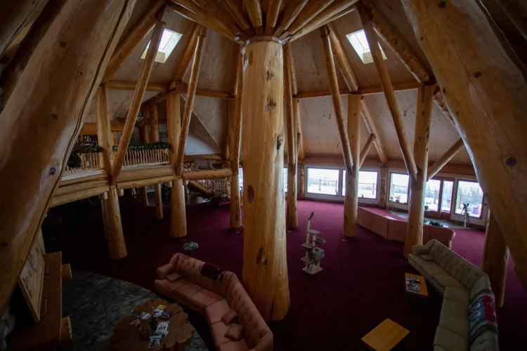 Gallery of the world's largest log home at Moberly Lake, featuring exterior views, the great room's 52ft ceiling, aerial shots, dining area, home theater, wine cellar, kitchen, and workout room with a pool and hot tub.